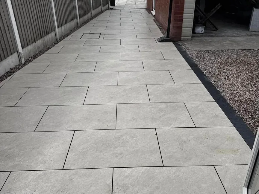 Finished grey porcelain path down the side of the house with a dark border detail