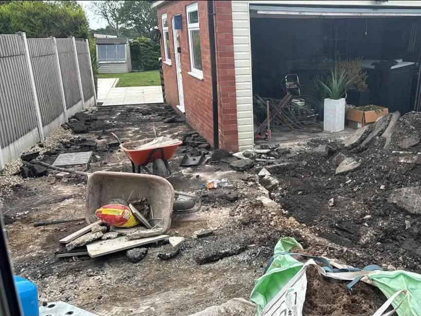 Side of a house dug out with a mini digger, broken concrete and rubble piled up