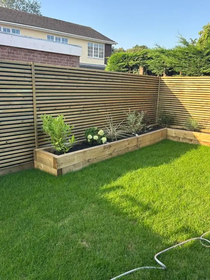 Slatted fence with sleeper planter and new lawn