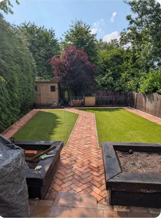 Herringbone brick path through a lawn between sleeper beds