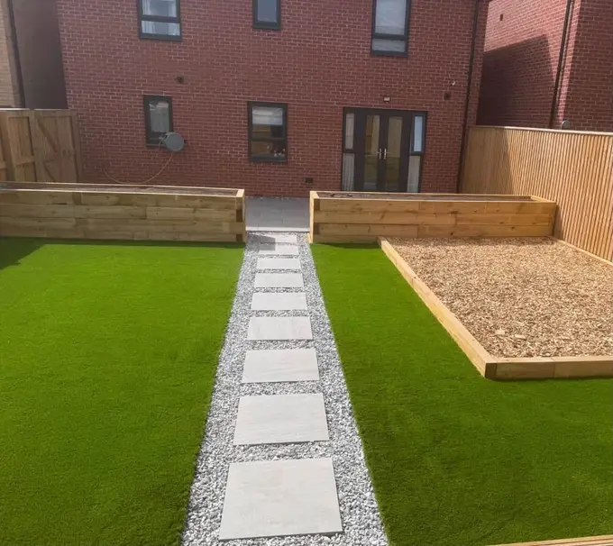 Artificial grass either side of a stepping stone path with gravel sleeper beds